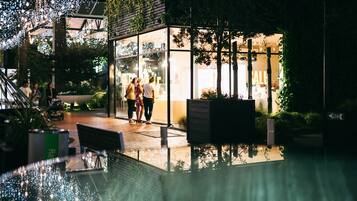An outdoor area with a glass enclosure, a wooden deck, and a reflective pool.