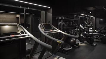 A modern gym with treadmills, weight machines, and a mirrored wall.