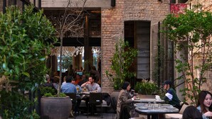 Un café en plein air avec des murs en briques, des plantes en pot et des tables avec des chaises.