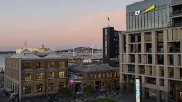 Un paysage urbain où se côtoient une architecture moderne et traditionnelle, avec notamment un bâtiment imposant arborant l’enseigne « EY » et une tour « Britomart ».