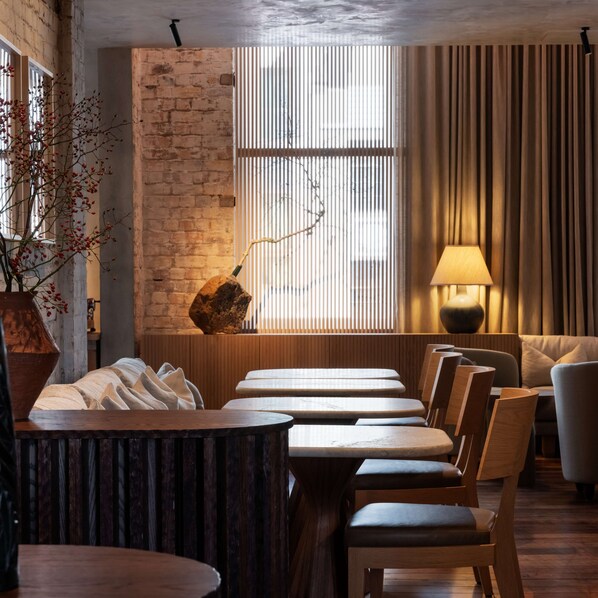 A restaurant with a brick wall, wooden tables, and chairs.