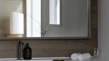 A modern bathroom with a large mirror, a white countertop, and a wooden vanity.