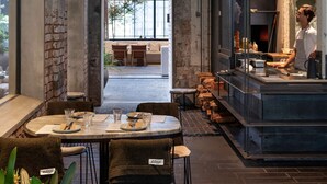 Un restaurant au décor rustique, avec des murs en briques apparentes, un bar et un espace repas comprenant des tables et des chaises.