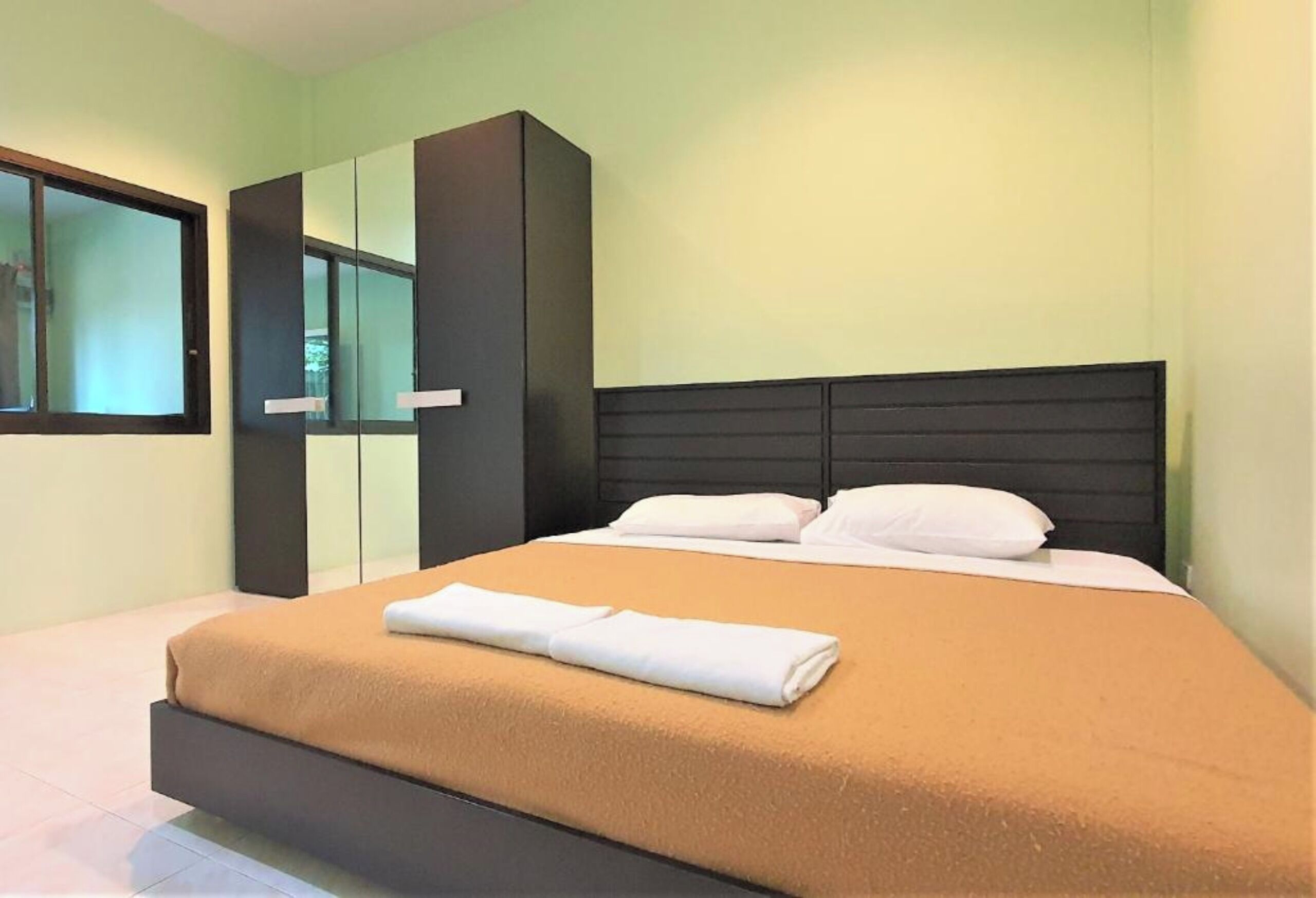 Une chambre à coucher moderne avec un lit, une grande armoire et une fenêtre.