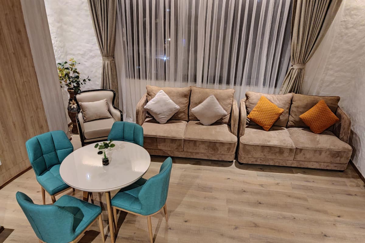 Een woonkamer met een beige bank, teal stoelen en een witte tafel.