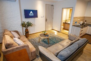 Uma sala de estar moderna com um sofá, uma mesa de centro e uma TV fixada na parede.