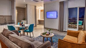 A modern hotel room with a dining area, a TV on the wall, and a view of the city at night. - Arushi Boutique Hotel (Kathmandu)