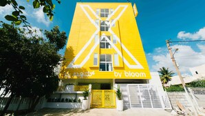 A yellow building with a distinctive X-shaped window design and the text "by bloom" on the facade. - X by Bloom - Hebbal (Bengaluru)