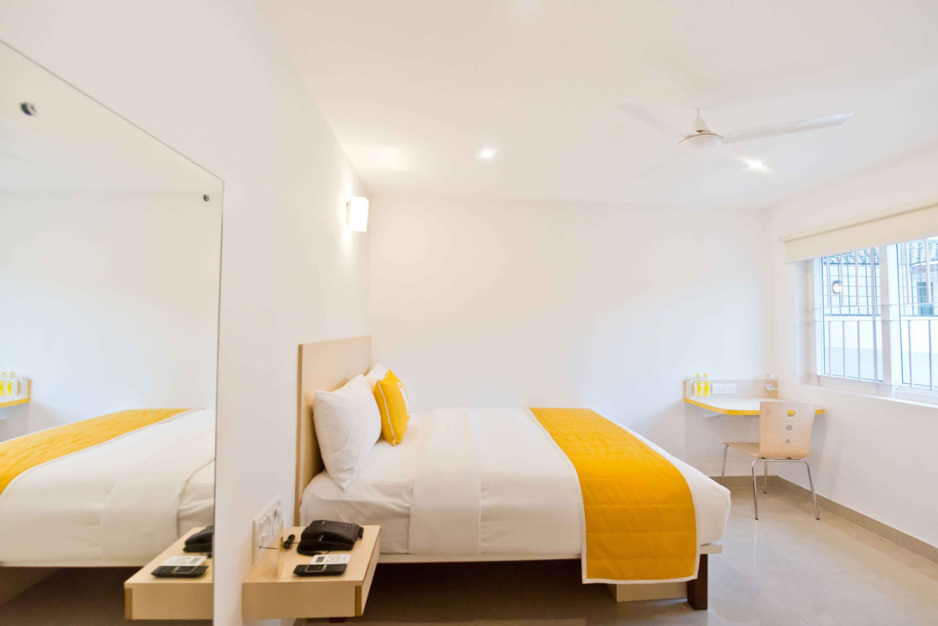 Una habitación de hotel con una cama grande, un escritorio, una silla y un ventilador de techo.