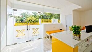 A modern kitchen with a white and yellow color scheme, a large window, and a bench. - X by Bloom - Hebbal (Bengaluru)