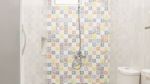 A bathroom with a shower, toilet, and a toilet paper holder. - Hotel O Monalisa Residence And Cafe (Padang)