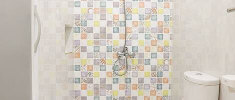 A bathroom with a shower, toilet, and a toilet paper holder.