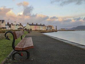 A bench along a waterfront promenade with colorful buildings in the background.
