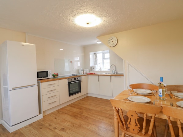 Functional kitchen with modern appliances, dining area, and clean design.