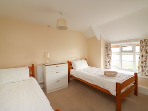 Cozy loft-style room with two beds, a bedside table, and a radiator, offering a comfortable space to rest.