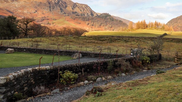 A stone wall with a grassy field and a mountain in the background. - Castle Lodge (Keswick)