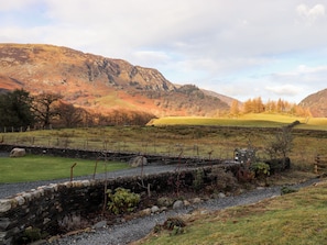 A stone wall with a grassy field and a mountain in the background. - Castle Lodge (Keswick)