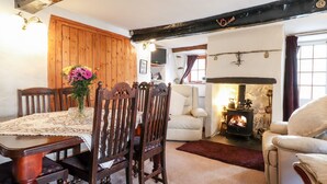 A cozy living room with a wooden dining table, two chairs, a fireplace, and a comfortable sofa. - Castle Lodge (Keswick)