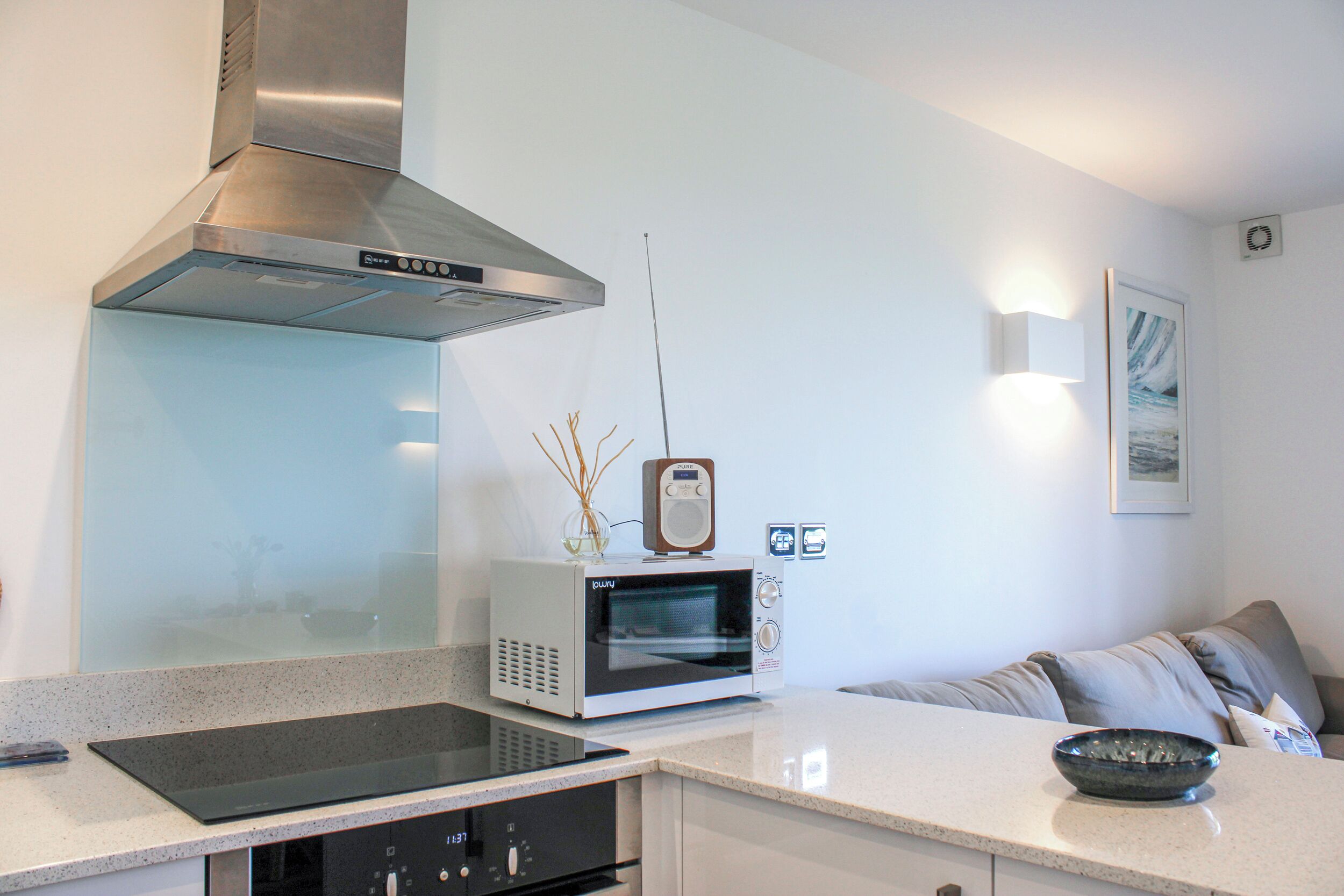 A modern kitchen with a built-in microwave, a stainless steel range hood, and a black induction cooktop.