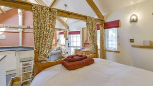 Een slaapkamer met een houten plafond, een bed met een wit dekbedovertrek, een rode handdoek en een nachtkastje van hout.