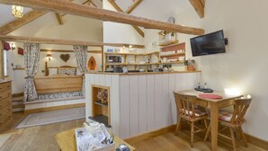 Een knus loft slaapkamer met een hoogslaper, een kleine kitchenette, een televisie en een eethoek met houten meubels.