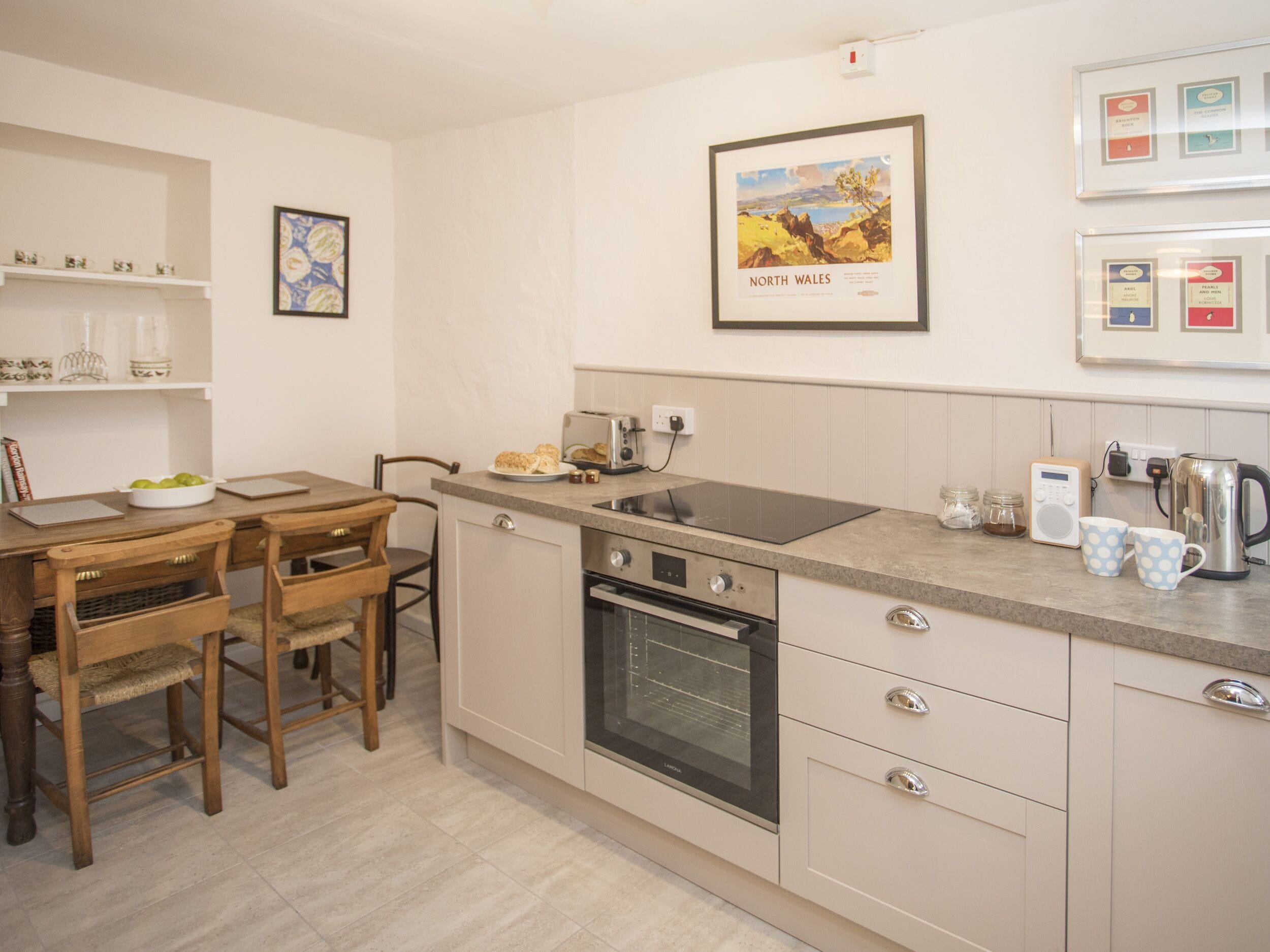 Eine moderne Küche mit Backofen, Kaffeemaschine und einem gerahmten Landschaftsbild an der Wand.
