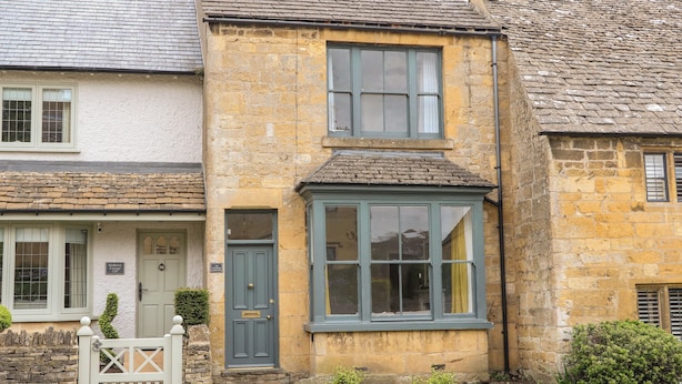 Une maison traditionnelle en pierre, à deux étages, avec une porte d’entrée et une petite fenêtre.