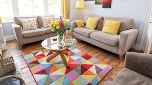 Un salon avec deux canapés, une table basse et un tapis coloré.