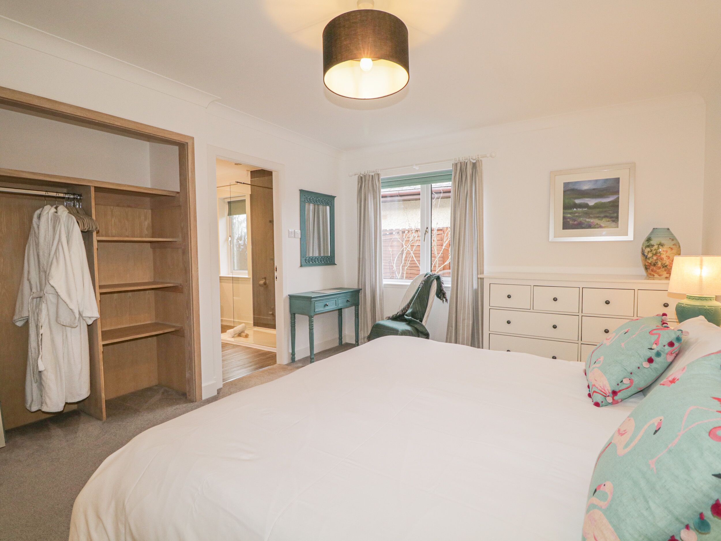 A bedroom with a large bed, a wooden wardrobe, a desk, and a chair.