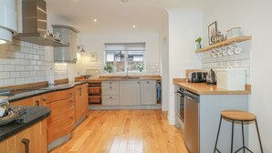 A modern kitchen with wooden cabinets, a stainless steel range hood, and a wooden countertop.