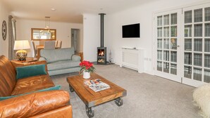 A living room with a sofa, coffee table, fireplace, and a television mounted on a wall.