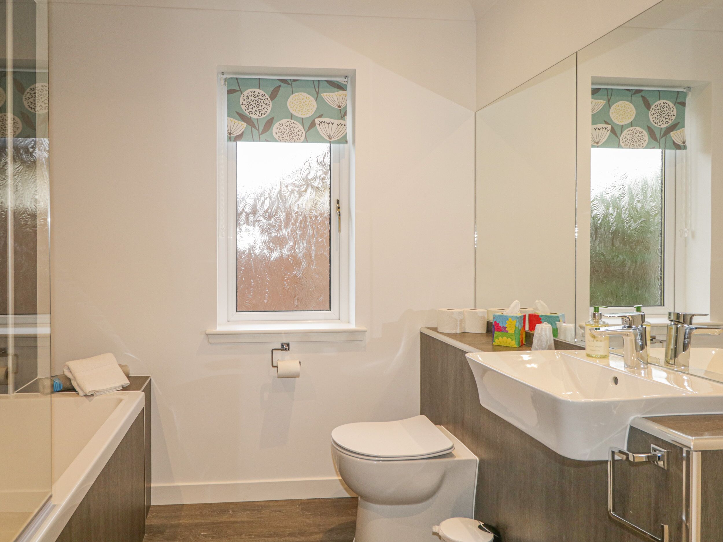 Un bagno moderno con il water, un lavandino e uno specchio grande.