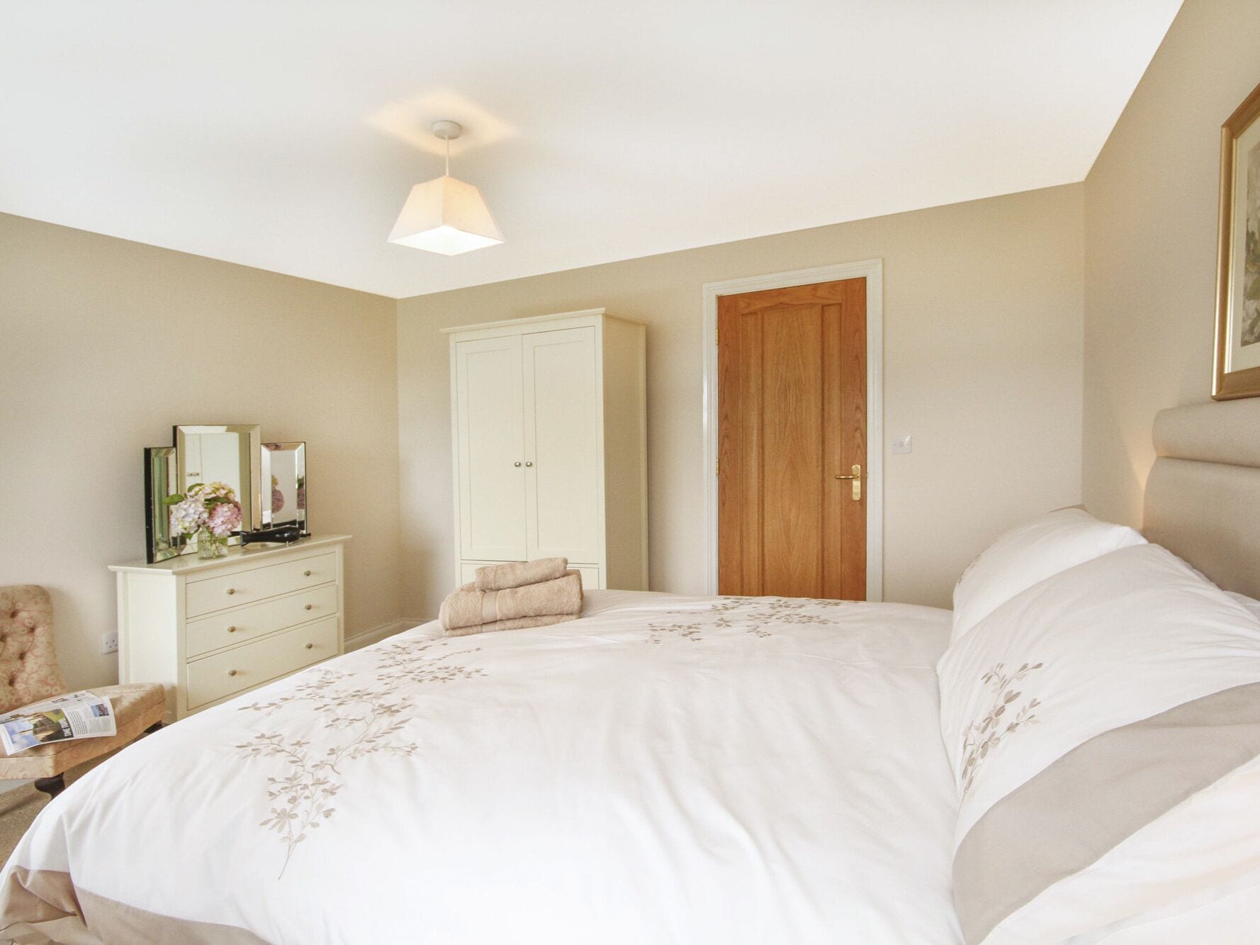 Une chambre à coucher avec un grand lit, une armoire, une porte en bois et une petite table avec une chaise.