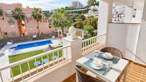 Ein Balkon mit Pool, Sitzgelegenheit im Freien und einem Esstisch.