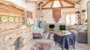 Un interior rústico con vigas de madera a la vista, una chimenea y una zona de estar acogedora.