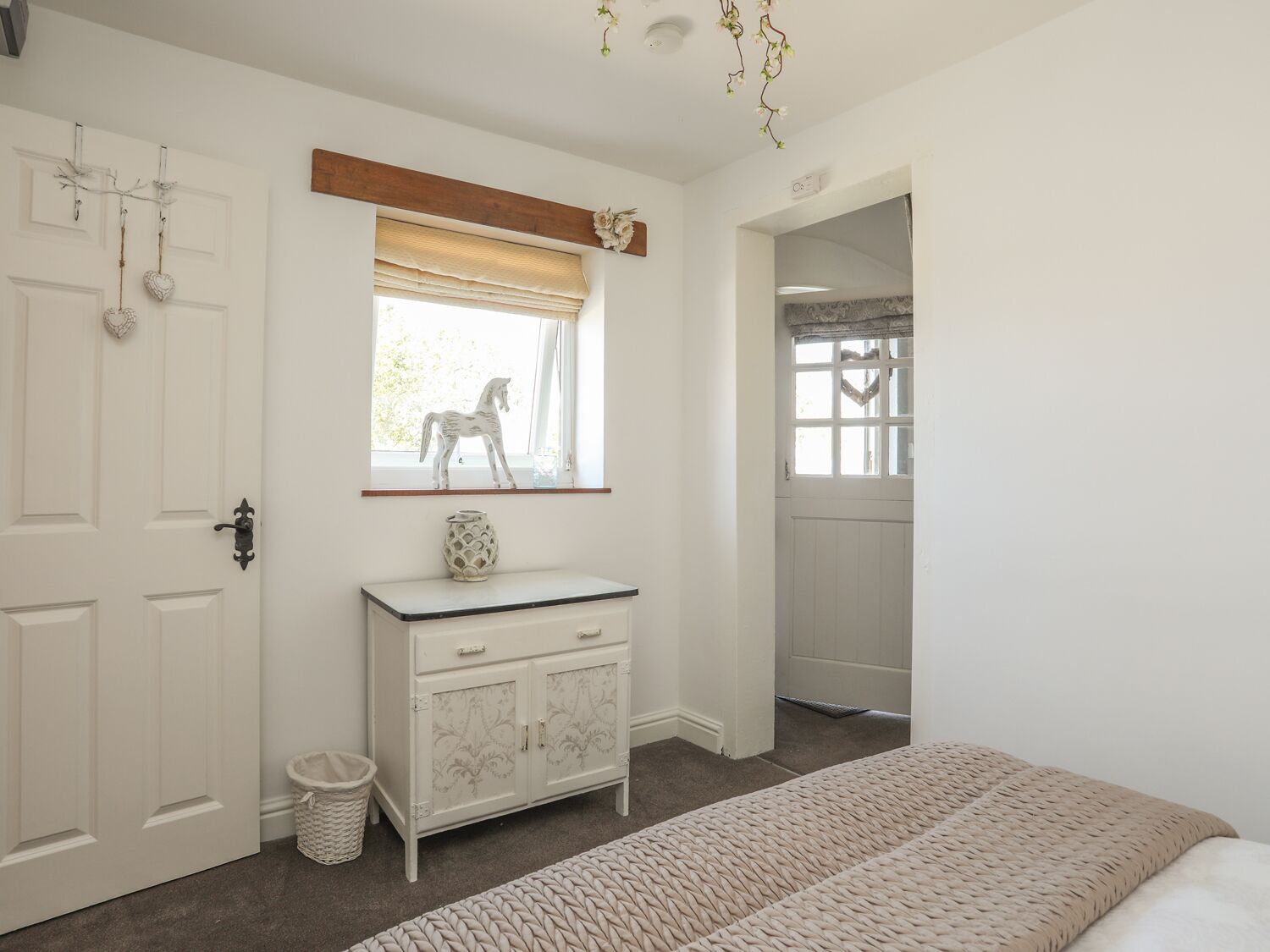 A bedroom with a bed, a dresser, a window with a view, and a door.