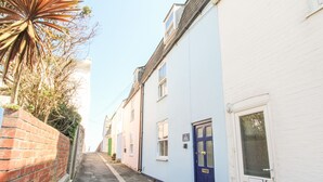A narrow street with a brick wall on one side and a row of buildings with numbered doors. - Firkin Cottage (Weymouth)