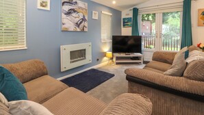 A living room with a TV, two sofas, a fireplace, and artwork on the walls. - 40 Skiptory Howe (Windermere)