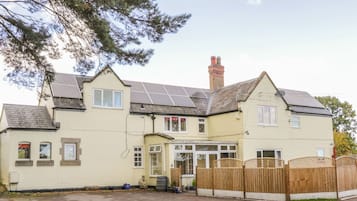 Stylish two-story home with a central entrance, glass door, and solar panels on the roof.