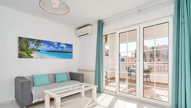 A bright living room with a sofa, a coffee table, and a large window with teal curtains. - Suite Nº 5 (1 double room and 1 single room) (Nerja)