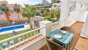 A balcony with a table set for two, overlooking a swimming pool and a garden. - Suite Nº 5 (1 double room and 1 single room) (Nerja)