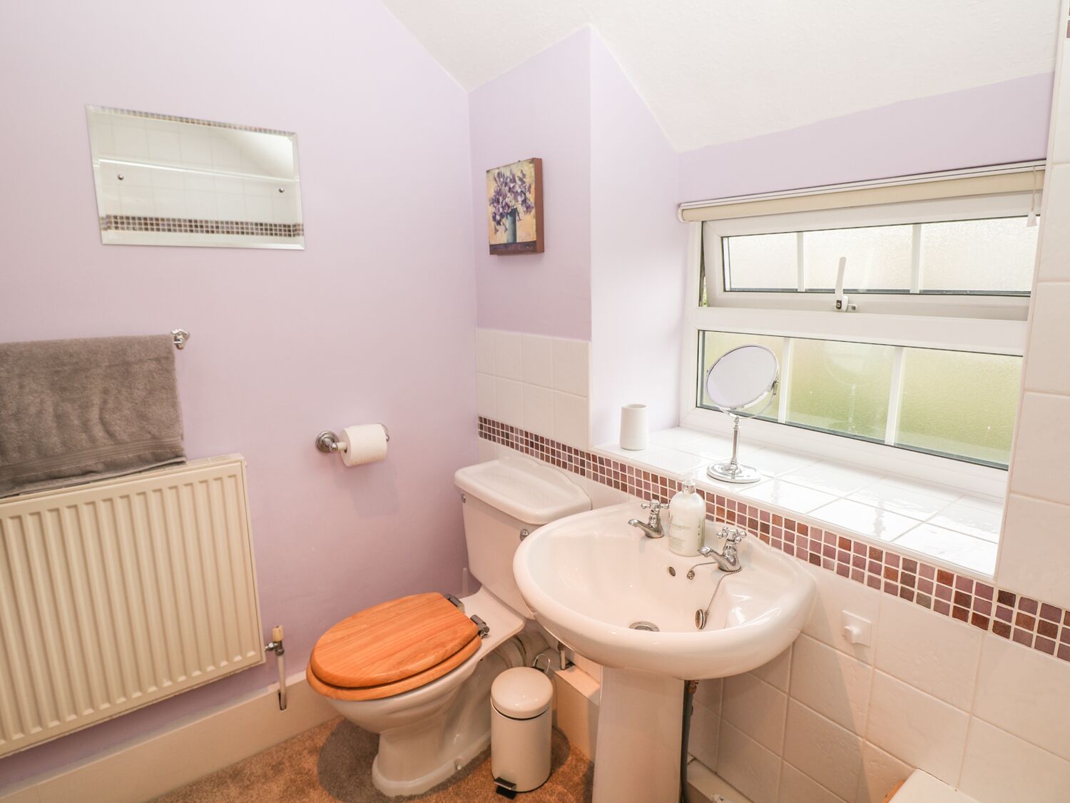 A bathroom with a toilet, sink, and window.