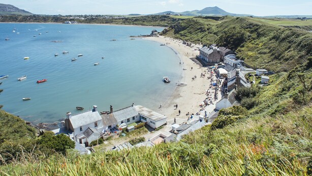 Uma vila costeira com uma praia, barcos e casas.