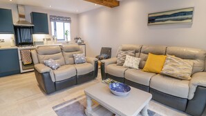 A modern living room with two leather sofas, a coffee table, and a kitchen in the background. - 7evern @ Porth Farm (Caersws)