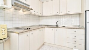 Une cuisine moderne avec des meubles blancs, un évier en acier inoxydable et une cuisinière intégrée.