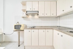 A kitchen with white cabinets, a granite countertop, and a vintage television. - Suite Nº 8 (1 double room) (Nerja)