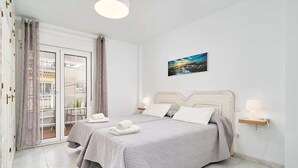 Une chambre avec deux lits, un balcon et un tableau au mur.