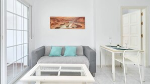 A modern living room with a sofa, a glass coffee table, a desk with a chair, and a painting on the wall. - Suite Nº 9 (2 double rooms) (Nerja)