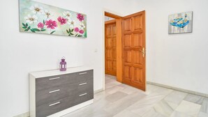 A hallway with a wooden door, a grey cabinet with drawers, and two floral paintings on the walls. - BB Suite (3 double rooms) (Nerja)