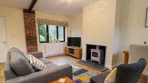 A cozy living room with a sofa, armchair, TV, fireplace, and a small wooden table.